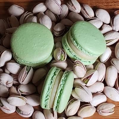 Pistachio macarons on a bed of pistachio nuts
