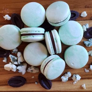 Light Blue colored macarons on a table with crumbled chocolate and Bleu Cheese