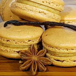 tan colored macarons in a stack with a star anise seed pod and a vanilla bean